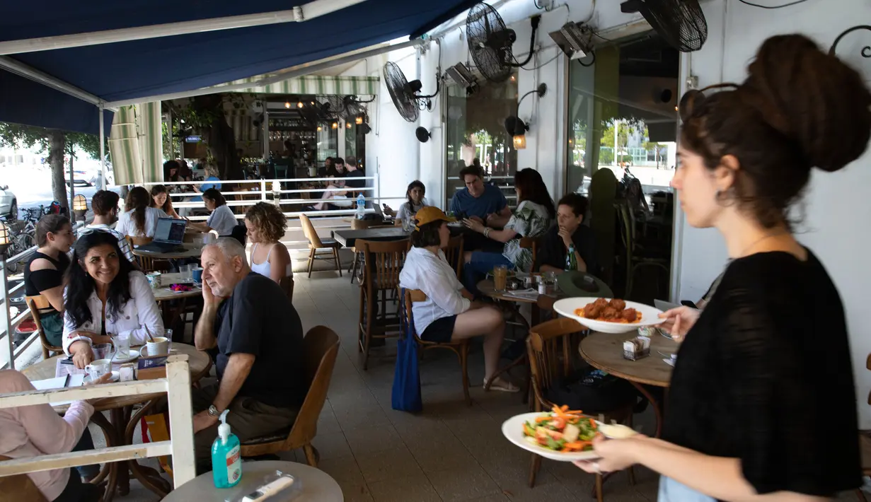 Seorang pramusaji menyajikan makanan di sebuah restoran di Tel Aviv, Israel pada Rabu (27/5/2020). Setelah lebih dari dua bulan ditutup untuk membendung penularan virus corona, restoran hingga kafe di Israel diizinkan dibuka kembali hari Rabu, 27 Mei. (AP Photo/Sebastian Scheiner)
