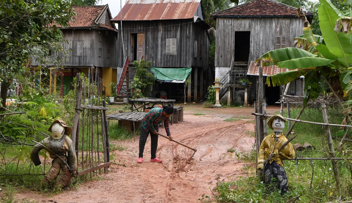 Dua orang-orangan sawah diikat ke pagar depan sebuah rumah di provinsi Kampong Cham, Kamboja, 11 Oktober 2020. Para petani di desa itu menggunakan orang-orangan sawah atau disebut juga Tim Mong untuk menangkal virus corona  Covid-19 berdasarkan kepercayaan yang mereka yakini. (TANG CHHIN Sothy/AFP)