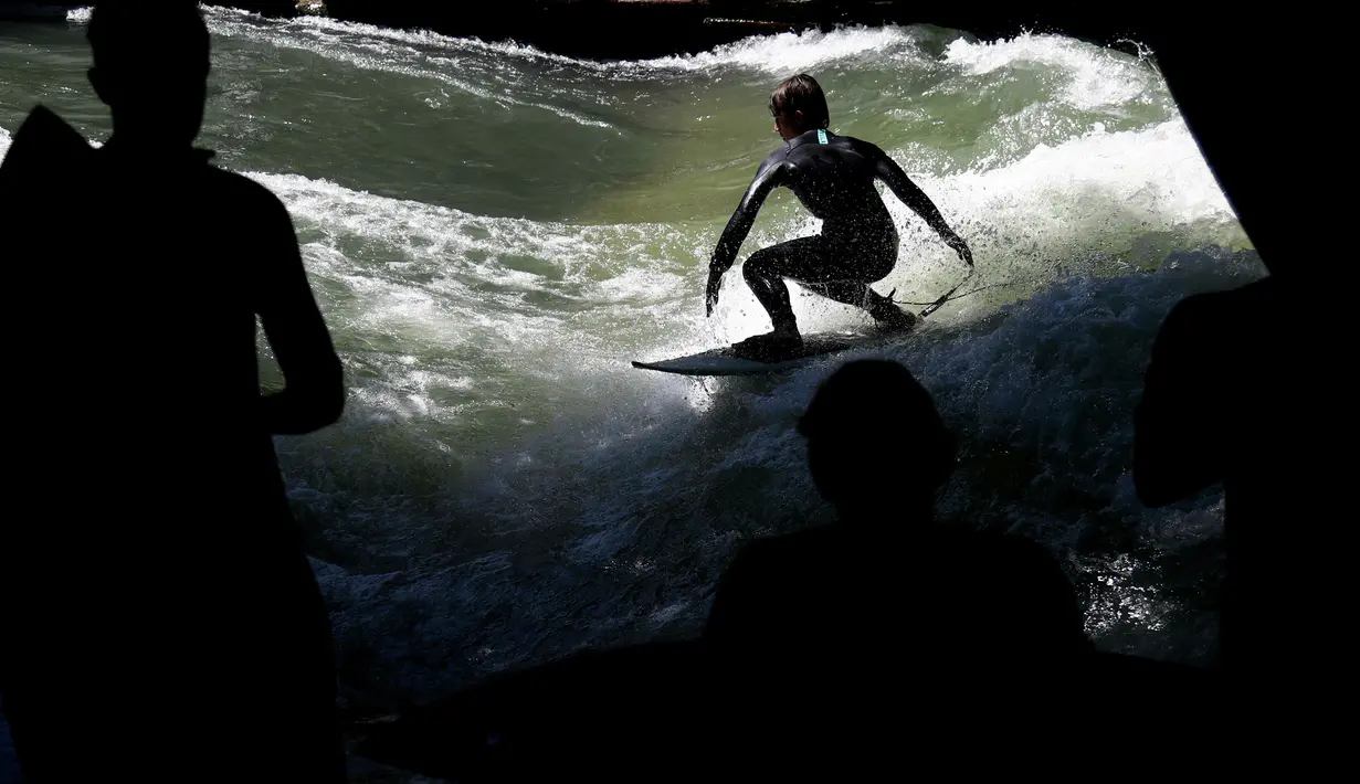 Seorang pria berusaha menaklukkan ombak buatan saat bermain surfing di sungai 'Eisbach' di taman English Garden di Munich, Jerman (24/6/2019). Eisbach merupakan sungai buatan dengan panjang dua kilometer dan arusnya pun merupakan buatan. (AP Photo/Matthias Schrader)
