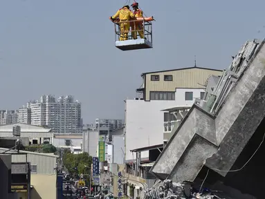 Lee Tsung-tien (42) diangkat dengan menggunakan crane oleh regu penyelamat di apartemen yang ambruk akibat gempa di kota Tainan, Taiwan, Senin (8/2). Dua korban berhasil diselamatkan setelah terperangkap selama lebih dari 50 jam. (AFP PHOTO/Sam Yeh)