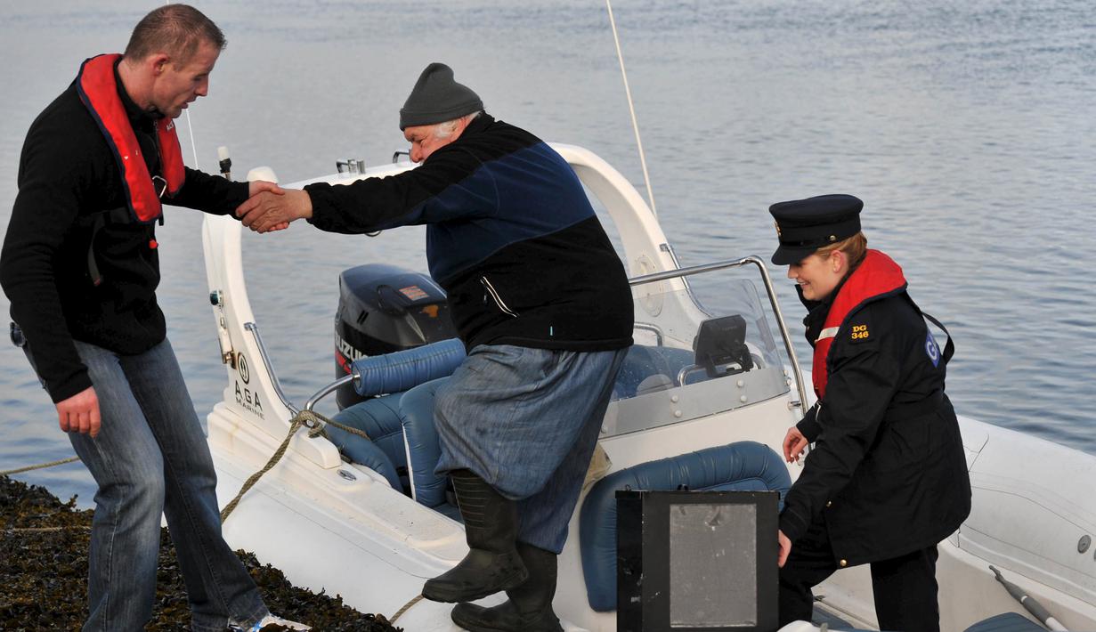 Polwan Margaret Byrne diantar menggunakan kapal ketika mengawal kotak suara di Inishfree, sebuah pulau terpencil di lepas pantai Donegal, Irlandia, Kamis (25/2). Irlandia akan menggelar pemilu pada 26 Februari. (REUTERS/Clodagh Kilcoyne)