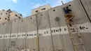 Seorang pria Palestina menggunakan tangga memanjat tembok Israel yang kontroversial saat akan salat Jumat pertama Ramadan di masjid Al-Aqsa, Yerusalem (10/5/2019). (Reuters/Mohamad Torokman)