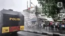 Warga saat menyaksikan petugas kepolisian menyemprotkan cairan disinfektan menggunakan kendaraan meriam air di Kawasan Petamburan, Jakarta, Minggu (22/11/2020). (merdeka.com/Iqbal S. Nugroho)