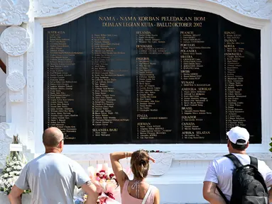 Para wisatawan asing berdiri di depan monumen Bom Bali 2002 saat upacara peringatan untuk menandai peringatan ke-22 di Kuta dekat Denpasar, Bali, pada Sabtu 12 Oktober 2024. (SONNY TUMBELAKA/AFP)