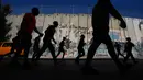 Bukan sekadar ajang olahraga, Maraton Internasional Palestina menjadi medium untuk menyoroti berbagai pembatasan pergerakan yang dialami warga Palestina di bawah pendudukan Israel. Tampak dalam foto, para pelari melewati tembok pemisah Israel saat mereka berkompetisi dalam Maraton Palestina di kota Betlehem, Tepi Barat, Jumat 8 Mei 2026. (AP Photo/Mahmoud Illean)