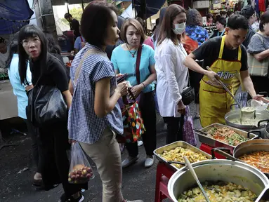 Karyawan perempuan membeli makanan sebelum mereka pergi bekerja di sebuah gang, yang terkenal dengan pedagang kaki lima dan pakaian, di pusat Bangkok, Thailand (8/11/2019). (AP Photo/Aijaz Rahi)