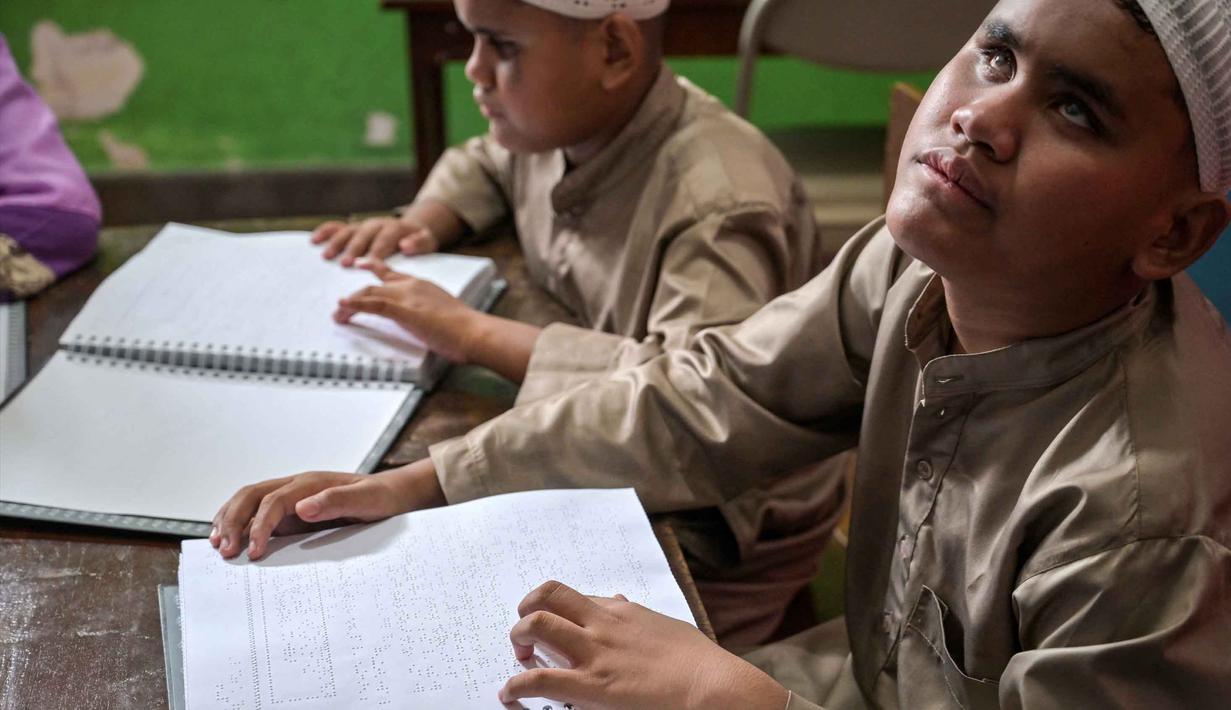 Meskipun bentuknya berbeda dari huruf Arab visual, setiap karakter Braille merupakan kombinasi titik yang melambangkan huruf tertentu. Tampak dalam foto, para siswa tunanetra membaca Al-Quran dalam huruf Braille selama bulan suci Ramadan 1447 Hijriah di sebuah sekolah di Surabaya, Jawa Timur, pada 27 Februari 2026. (JUNI KRISWANTO/AFP)