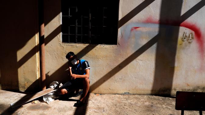 Seorang pria yang menjalanikarantina berbicara melalui handphone di teras sekolah, Ciudad del Este, Paraguay, Rabu (24/6/2020). Ada 15 ribu warga Paraguay yang masih menunggu untuk masuk kembali ke negara itu di negara-negara tetangga seperti Brasil dan Argentina. (AP Photo/Jorge Saenz)