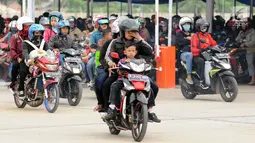 Pemudik membawa anaknya saat akan memasuki kapal penyereberangan di Dermaga 6 Pelabuhan Merak, Banten, Kamis (22/6). Meski berbahaya, sejumlah pemudik masih nekat membawa anak mereka dengan sepeda motor. (Liputan6.com/Helmi Fithriansyah)