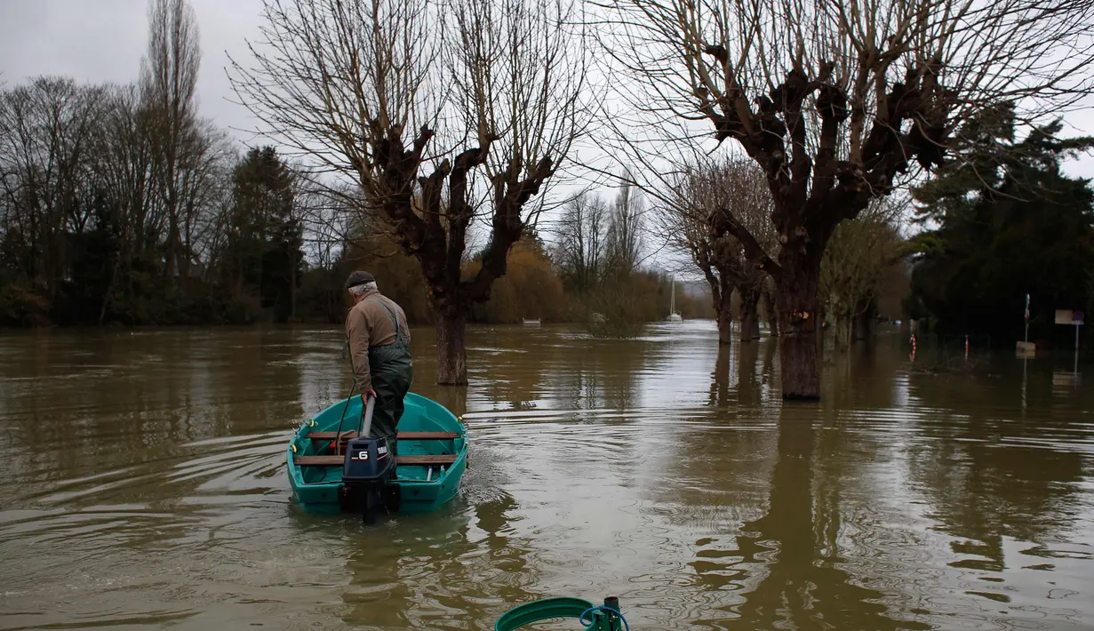 Marcel Leclercq menggunakan perahu di jalan yang banjir di pulau Vaux, sebelah barat Paris, (30/1). Sungai Seine yang meluap akibat hujan deras dalam 50 tahun telah menelan dermaga di Paris, Prancis. (AP Photo / Thibault Camus)