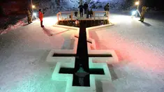 Penganut Kristen Ortodoks terjun ke kolam air es selama perayaan liburan Epiphany di Desa Tyarlevo di luar Saint Petersburg, Rusia, Kamis (18/1). (Olga MALTSEVA/AFP)