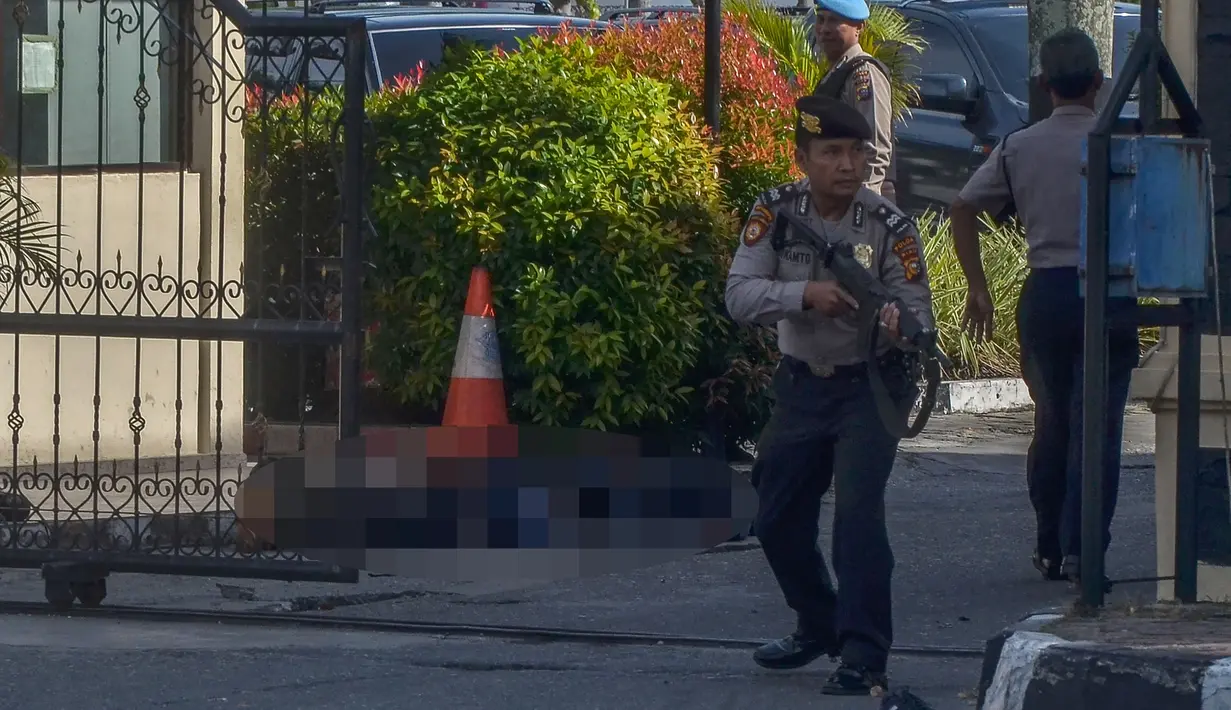 Petugas kepolisian berjaga setelah serangan di luar markas polisi di Pekanbaru, Riau (16/5). Empat pelaku penyerangan ditembak dan tewas ketika mereka melakukan serangan.  (AFP Photo/Dedy Sutisna)