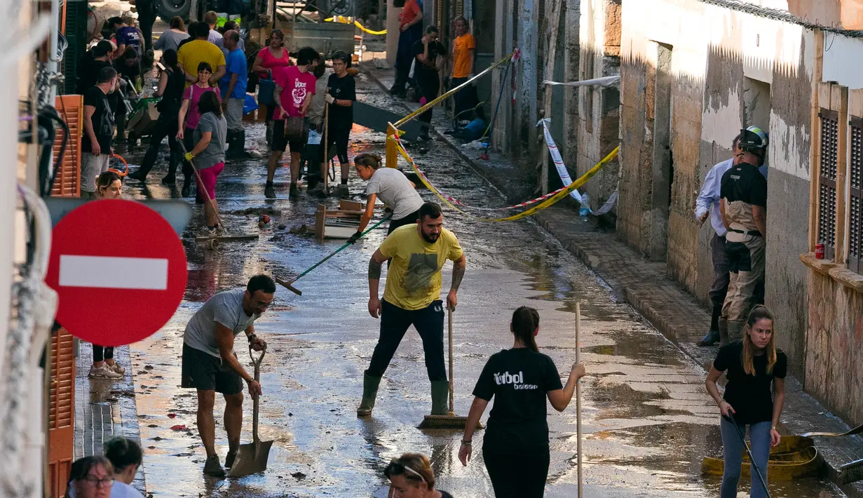 Sejumlah warga membersihkan rumah mereka yang terkena banjir bandang di Sant Llorenc, Mallorca, Spanyol (11/10). Banjir bandang tersebut telah menewaskan setidaknya 10 orang. (AP Photo/Francisco Ubilla)