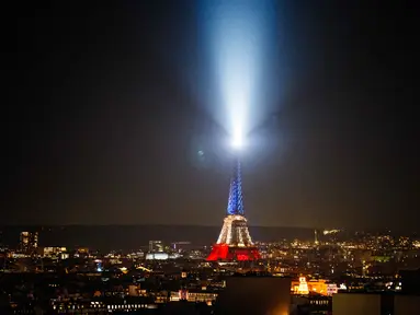 Foto ini menunjukkan Menara Eiffel yang diterangi dengan warna bendera nasional Prancis saat peringatan ke-10 serangan teroris Paris yang terjadi pada 2015, di Paris, pada 12 November 2025. Prancis memperingati satu dekade tragedi berdarah pada 13 November 2015. (Dimitar DILKOFF/AFP)