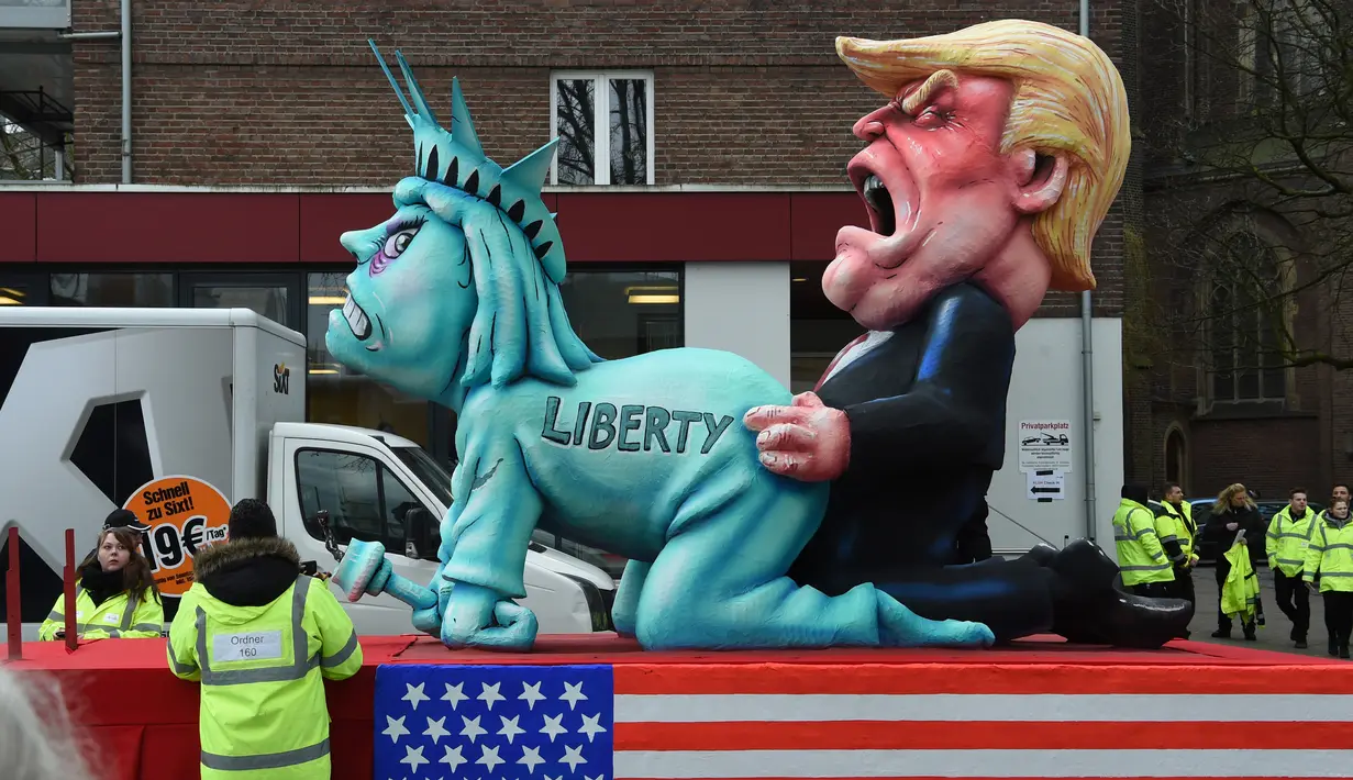 Sebuah patung berbentuk menyerupai Patung Liberty dan Presiden AS ikut dalam karnaval tradisional 'Rose Monday' di Dusseldorf, Jerman Barat, Senin (27/2). Karnaval 'Rose Monday' berisi sindiran satir para pemimpin dunia. (AFP PHOTO / Patrik STOLLARZ)