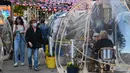 Orang-orang menikmati makanan di dalam tenda plastik untuk menjaga jarak di sebuah restoran di Manhattan, New York City, Kamis (15/10/2020). Konsep gelembung luar angkasa ini menawarkan sensasi tersendiri sekaligus berjaga-jaga dari resiko penularan COVID-19 bagi para pelanggan. (Angela Weiss/AFP)