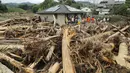 Petugas penyelamat dan penduduk memanfaatkan jeda hujan untuk membersihkan pohon-pohon, dan lumpur setinggi lutut yang memenuhi jalanan di Toho, prefektur Fukuoka, Jepang, Sabtu (8/7). (AFP PHOTO / JIJI PRESS)