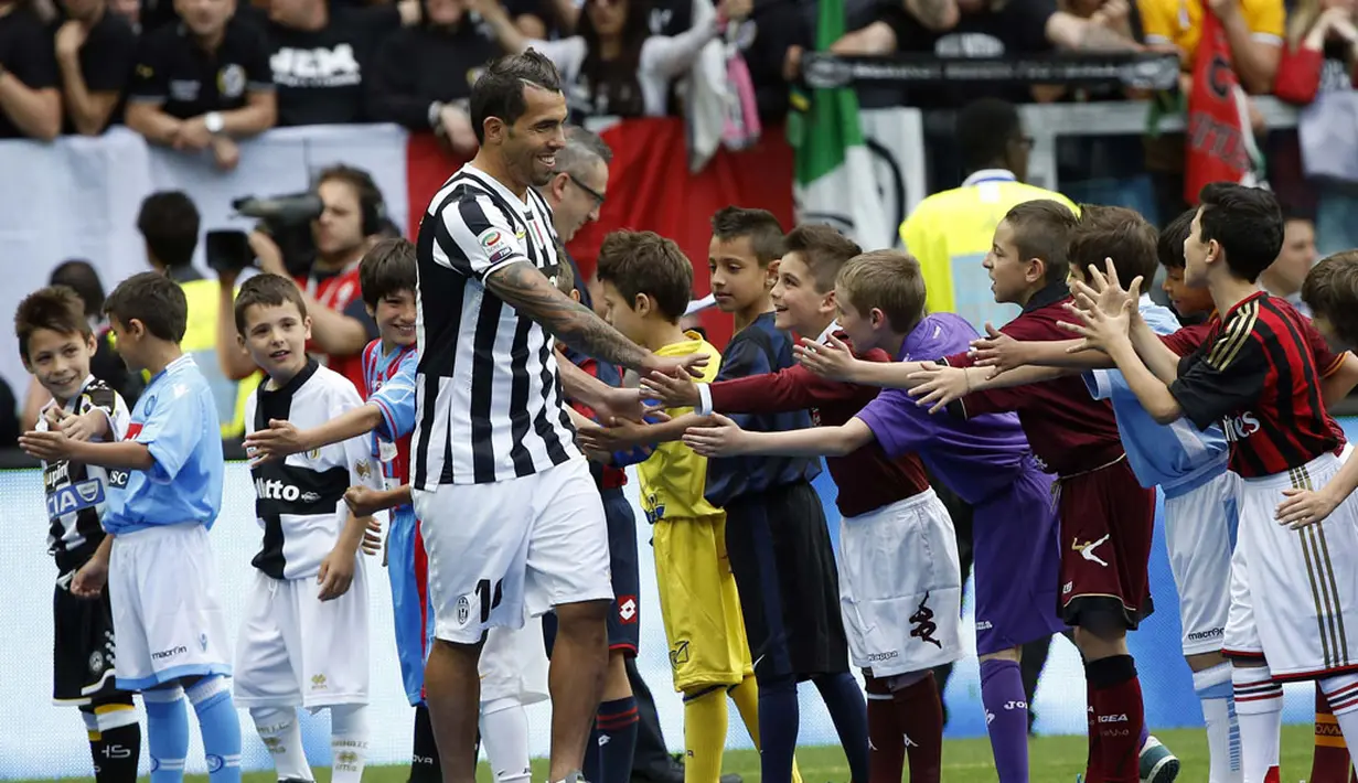 Pemain depan Juventus, Carlos Tevez berjabat tangan dengan anak-anak di akhir pertandingan melawan Cagliari sesaat sebelum memulai selebrasi gelar scudetto di Turin, (18/5/2014). (REUTERS/Alessandro Garofalo)