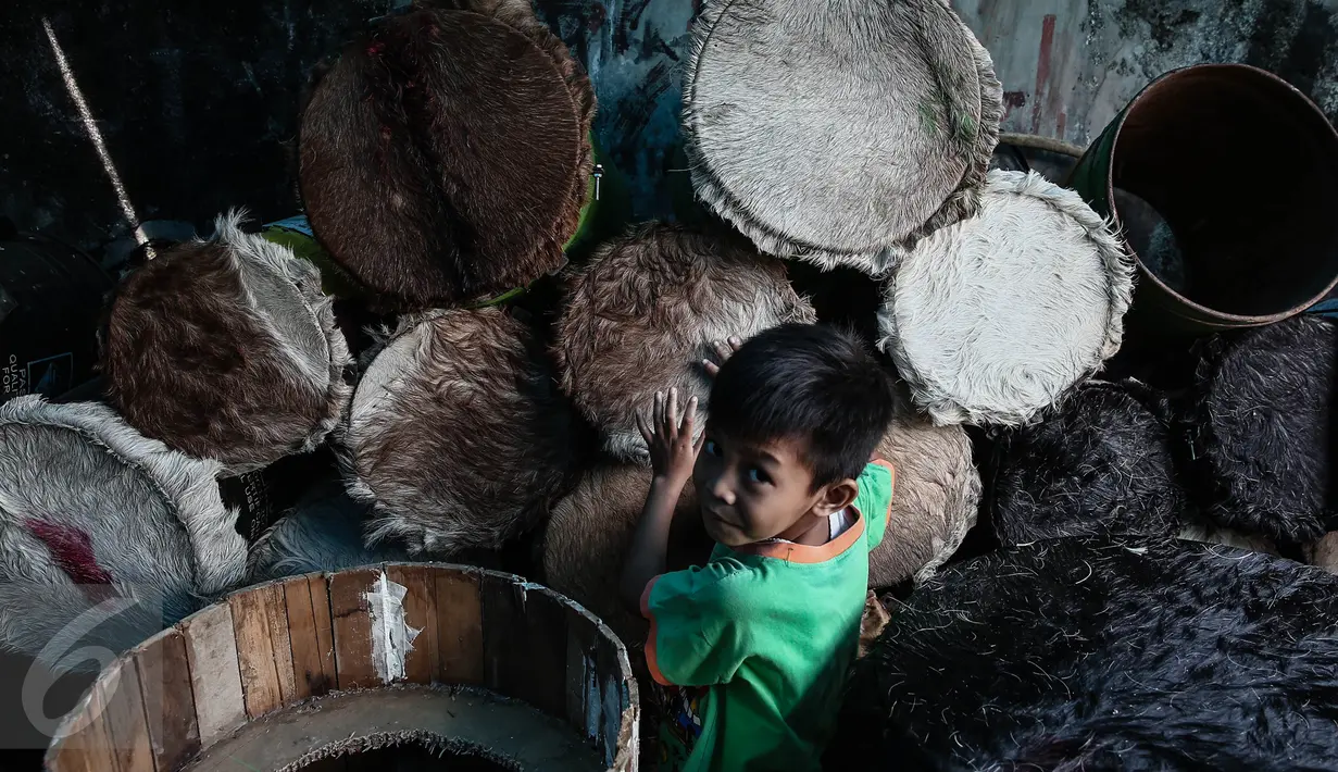 Seorang anak kecil mencoba bedug di tempat pembuatan bedug, kawasan Tanah Abang, Jakarta, Jumat (17/6). Aneka ragam bedug yang dijual dari harga Rp. 100 ribu hingga Rp 4 juta. (Liputan6.com/Faizal Fanani)