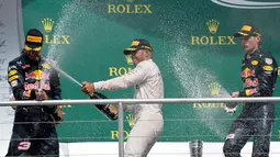 Juara GP Jerman, Lewis Hamilton (tengah) menyemprotkan sampanye ke juara dua GP Jerman, pembalap Red Bull Daniel Ricciardo saat merayakan kemenangan mereka di atas podium pada Grand Prix Formula 1 Jerman, Minggu (31/7). (THOMAS KIENZLE/AFP)