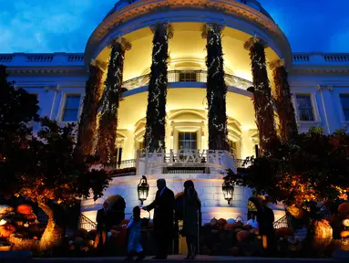 Presiden Amerika Serikat (AS) Donald Trump dan Ibu Negara Melania Trump memberikan permen kepada anak-anak selama yang hadir acara trick-or-treat pada perayaan Halloween di Gedung Putih, Washington, Minggu (28/10). (AP/Jacquelyn Martin)