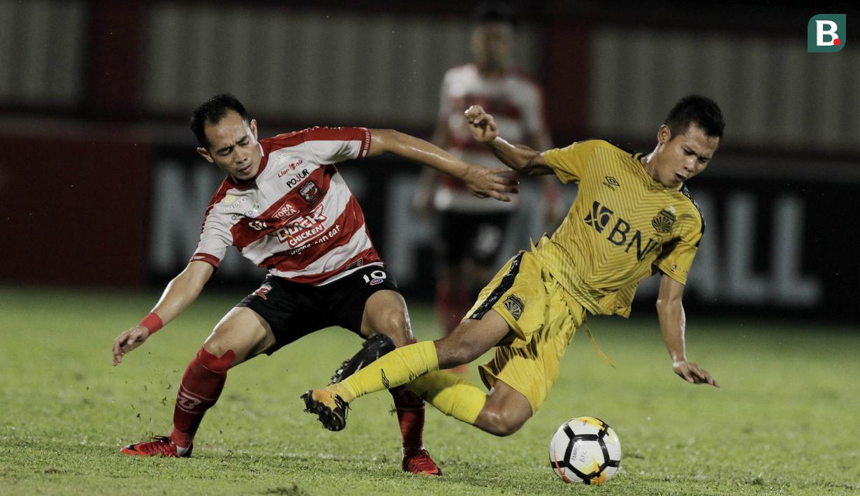 Gelandang Bhayangkara FC, Wahyu Subo Seto, terjatuh saat berebut bola dengan gelandang Madura United, Slamet Nurcahyo pada laga Liga 1 di Stadion PTIK, Jakarta, Kamis, (07/6/2018). (Bola.com/M Iqbal Ichsan)