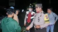Personel Polresta Pekanbaru memeriksa bawaan warga yang masih berkeliaran pada malam hari untuk mengantisipasi tindak pidana. (Liputan6.com/M Syukur)