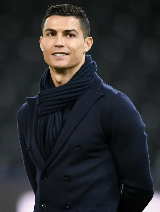 Penyerang Juventus, Cristiano Ronaldo tersenyum saat memeriksa lapangan di Stade de Suisse di Bern (11/12). Ronaldo tampil keren menggenakan setelan jas dengan syal di lehernya saat mengecek markas Young Boys. (AFP Photo/Fabrice Coffrini)