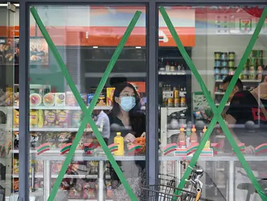 Orang-orang berbelanja di sebuah minimarket dengan jendela yang ditutup rapat saat Topan Super Ragasa mendekati Zhuhai, Provinsi Guangdong, Tiongkok Selatan, pada Selasa 23 September 2025. (Adek BERRY/AFP)