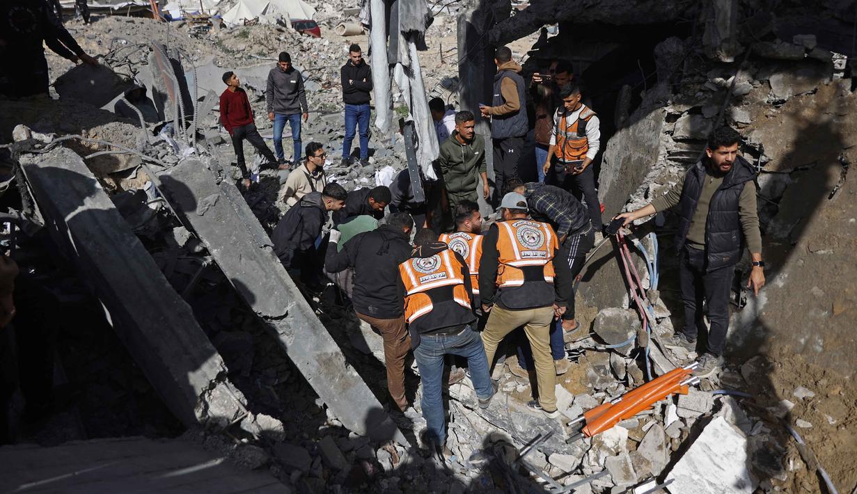 Sejak gencatan senjata mulai diberlakukan di Gaza, kedua pihak bertikai, Israel dan Hamas, saling menuduh telah melanggar kesepakatan. Tampak dalam foto, tim penyelamat dan warga yang menyaksikan kejadian tersebut memeriksa puing-puing kantor polisi Sheikh Radwan di Kota Gaza pada 31 Januari 2026. (Omar AL-QATTAA/AFP)