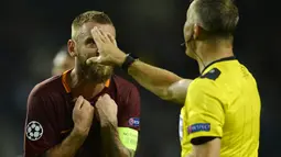 Kapten AS Roma, Daniele De Rossi (kiri) memprotes keputusan wasit, Bjorn Kuipers saat laga melawan FC Porto pada leg pertama  playoff Liga Champions 2016-2017 di Estadio Do Dragao, Kamis (18/8/2016) dini hari WIB. (AFP/Miguel Riopa)