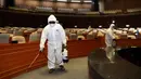 Pekerja dari Asosiasi Pengendalian Hama Korea menyemprotkan disinfektan di Majelis Nasional Seoul (25/2/2020). Pihak berwenang melaporkan 169 infeksi baru. Termasuk di antaranya seorang tentara AS, sehingga jumlah keseluruhannya menjadi 1.146. (AFP/Yonhap)