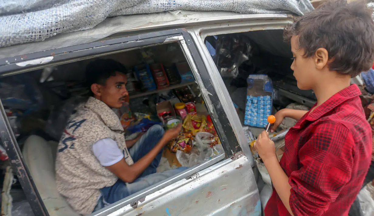 Majd al-Din al-Shamiri (16) melayani pembeli di toko darurat di kawasan Jabal Sabr, Yaman pada 28 September 2019. Majd al-Din al-Shamiri mengubah mobil keluarganya yang rusak parah, akibat perang yang melanda, menjadi toko darurat untuk membantu keluarganya mencari nafkah. (Ahmad AL-BASHA/AFP)