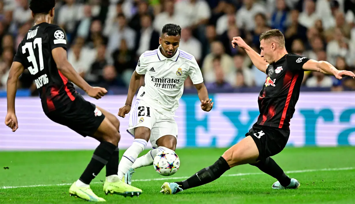 Pemain depan Real Madrid Rodrygo (tengah) berebut bola dengan pemain Red Bull Leipzig Abdou Diallo dan Willi Orban pada matchday 2 Liga Champions berlangsung di Santiago Bernabeu, Kamis (15/9/2022) dini hari WIB. Real Madrid menang susah payah 2-0 kala menjamu RB Leipzig. (Photo by JAVIER SORIANO / AFP)