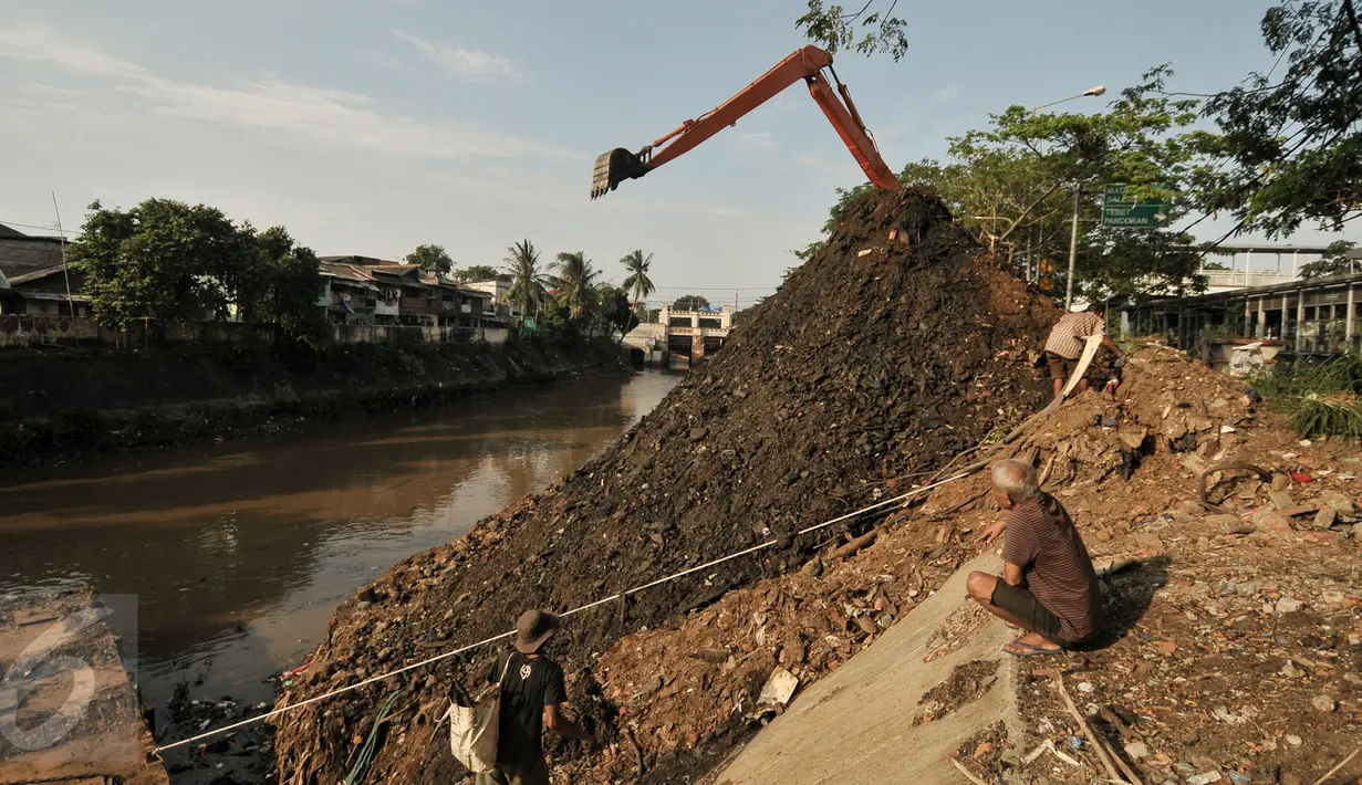 Warga melihat aktifitas pengerukan tumpukan sisa lumpur dan tanah yang menumpuk di pinggir kali Ciliwung, Jakarta, Kamis (28/7). Dinas Tata Air DKI Jakarta bersihkan tumpukan tanah dan lumpur sisa pengerukan kali Ciliwung. (Liputan6.com/Yoppy Renato)