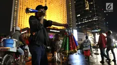Pedagang menjual terompet pada malam pergantian tahun di kawasan Bundaran HI, Jakarta, Senin (31/12). Pergantian tahun dimanfaatkan pedagang untuk mencari keuntungan dengan berjualan pernak pernik tahun baru.(Liputan6.com/Angga Yuniar)