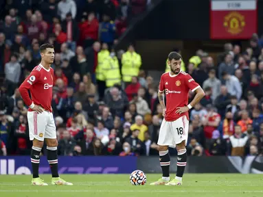 Pemain Manchester United Cristiano Ronaldo (kiri) dan Bruno Fernandes (tengah) bereaksi setelah pemain Liverpool Mohamed Salah mencetak gol ke gawang mereka pada pertandingan Liga Inggris di Old Trafford, Manchester, Inggris, Minggu (24/10/2021). Liverpool menang 5-0. (AP Photo/Rui Vieira)