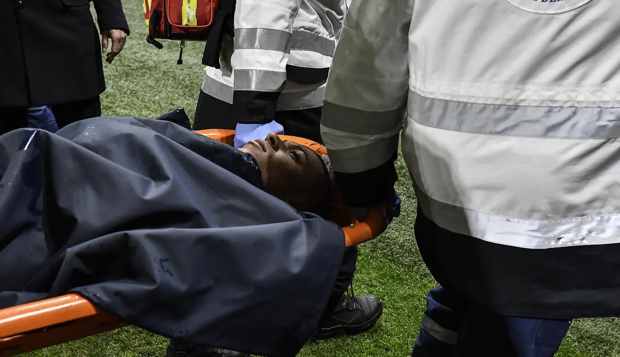 Pemain Paris Saint-Germain, Kylian Mbappe ditandu ke luar lapangan saat lanjutan Ligue 1 di Groupama Stadium, Senin (22/1). Mbappe mengalami cedera setelah berbenturan dengan kiper Olympique Lyon, Anthony Lopes. (AFP PHOTO / JEFF PACHOUD)