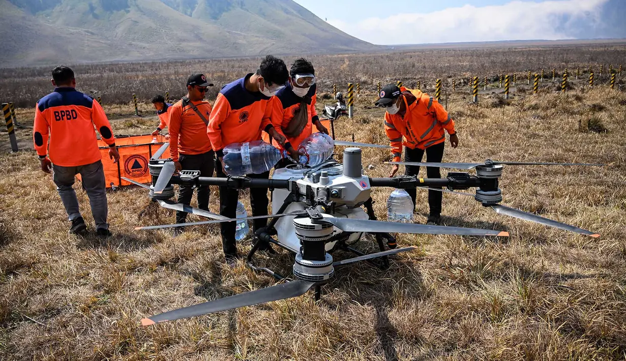 Petugas Badan Penanggulangan Bencana Daerah (BPBD) Jawa Timur mengisi tangki drone water spray yang digunakan untuk memadamkan kebakaran hutan dan lahan (karhutla) di kawasan Taman Nasional Bromo Tengger Semeru (TNBTS), Kabupaten Probolinggo, Jawa Timur, Kamis (6/8/2026). (AFP/ Juni Kriswanto)