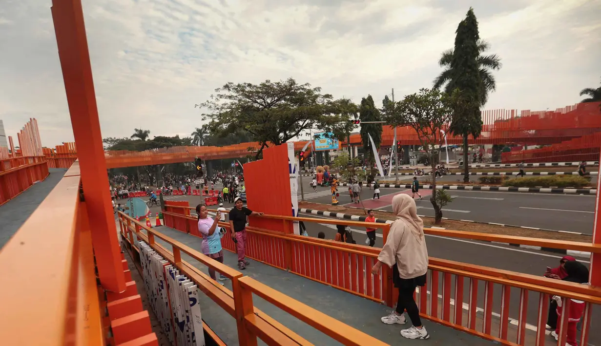 Warga beraktivitas di sekitar Jembatan Penyeberangan Orang (JPO) di Jalan Tegar Beriman, Cibinong, Kabupaten Bogor, Jawa Barat, Minggu (14/6/2026). (Kapanlagi.com/Budy Santoso)