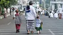 Seorang pria bersama dua orang anak berjalan menuju tempat pelaksanaan salat Idul Fitri 1438 H di kawasan Jatinegara, Jakarta, Minggu (25/7). Ruas Jalan Jatinegara Barat disulap menjadi tempat pelaksanaan salat Ied. (Liputan6.com/Yoppy Renato)