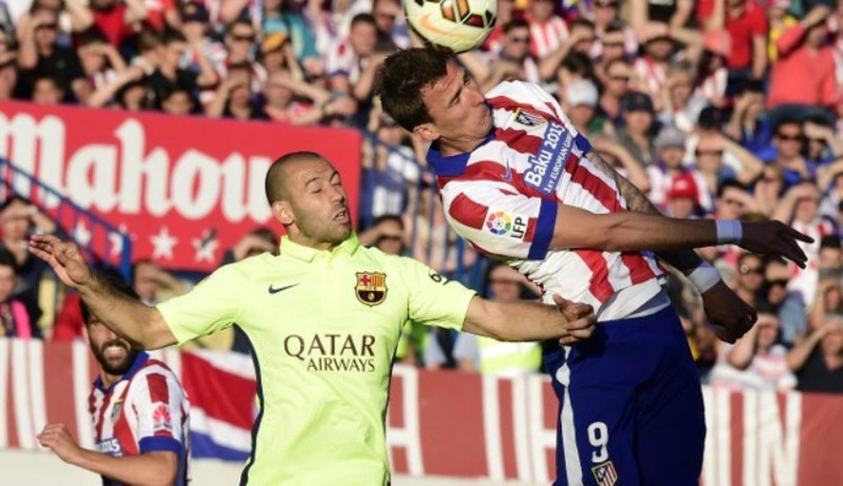 Pemain Barcelona, Javier Mascherano (kiri) berebut bola dengan striker Atletico Madrid, Mario Mandzukic. (AFP PHOTO / GERARD JULIEN)