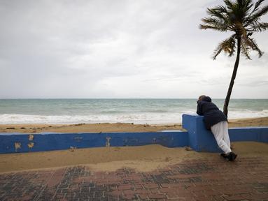 Seorang pria berdiri di dekat pantai sebelum kedatangan Badai Tropis Fiona di San Juan, Puerto Rico, Sabtu (17/9/2022). Fiona diperkirakan akan menjadi badai saat mendekati Puerto Rico dan akan melintasi wilayah teritori Amerika Serikat pada Minggu pagi. (AP Photo/Alejandro Granadillo)