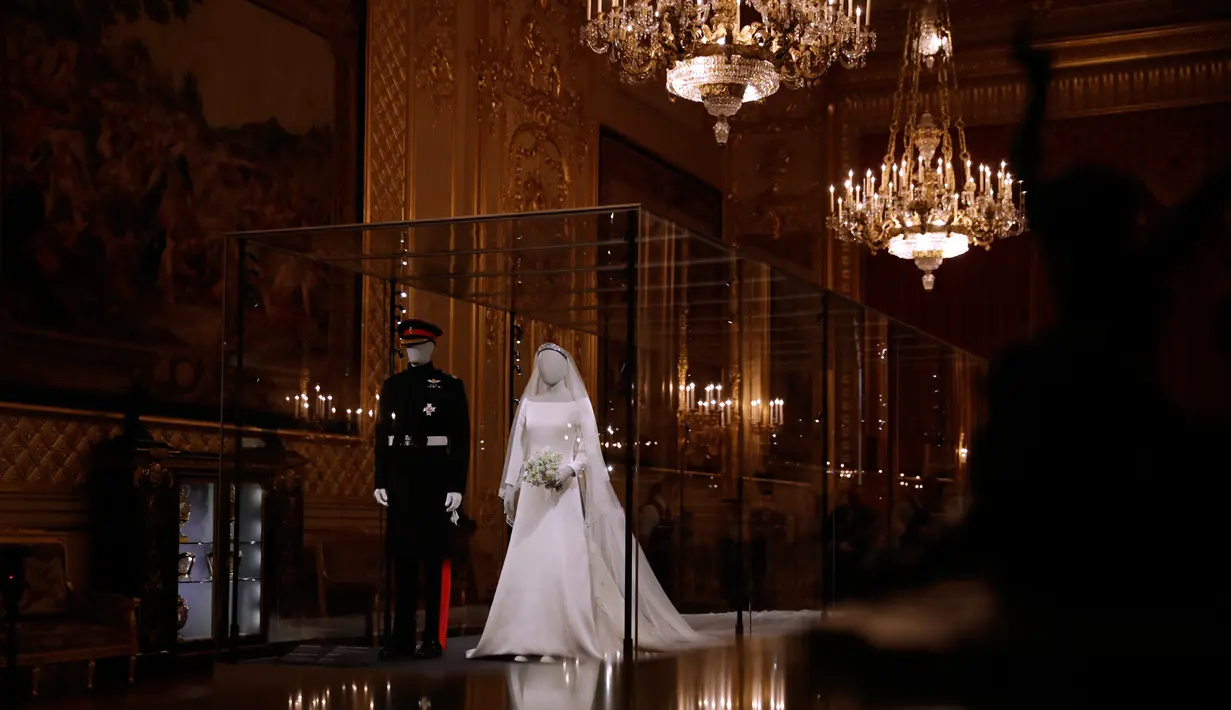 Gaun pernikahan Meghan Markle dan Pangeran Harry ditampilkan pada pameran A Royal Wedding di Kastil Windsor, London, 25 Oktober 2018. Gaun yang dikenakan Meghan, dipajang di kotak kaca besar di samping kostum pernikahan Pangeran Harry. (AP/Matt Dunham)