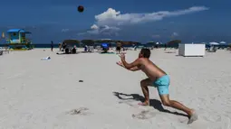 Pengunjung bermain bola di Miami Beach di Florida, Rabu (10/6/2020). Pantai Miami dibuka hari ini untuk pertama kalinya setelah hampir tiga bulan ditutup guna menekan jumlah penyebaran corona Covid-19. (CHANDAN KHANNA / AFP)