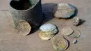 Sebuah bejana perunggu berisi koin emas kuno dan anting-anting ditemukan di sebuah situs penggalian di kota Mediterania Kaisarea, Israel, Senin (3/12). Koin-koin emas dalam bejana tersebut diperkirakan dibuat pada akhir abad ke-11. (JACK GUEZ/AFP)