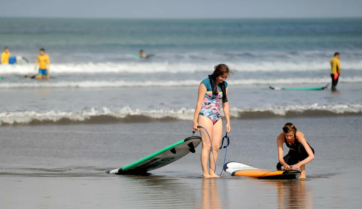 Dua turis bermain surfing di Pantai Kuta di Denpasar, Bali (27/9). Gunung Agung kemungkinan akan meletus untuk pertama kalinya sejak lebih 50 tahun lalu. (AFP Photo/Sony Tumbelaka)