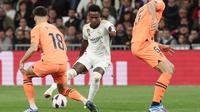 Pemain Real Madrid, Vinicius Junior berusaha melewati pemain Valencia pada laga Liga Spanyol di Stadion Santiago Bernabeu, Sabtu (11/11/2023). Berkat kemenangan ini, Real Madrid tetap berada di peringkat dua klasemen sementara La Liga, sementara Valencia tertahan di peringkat 10. (AFP/Thomas Coex)