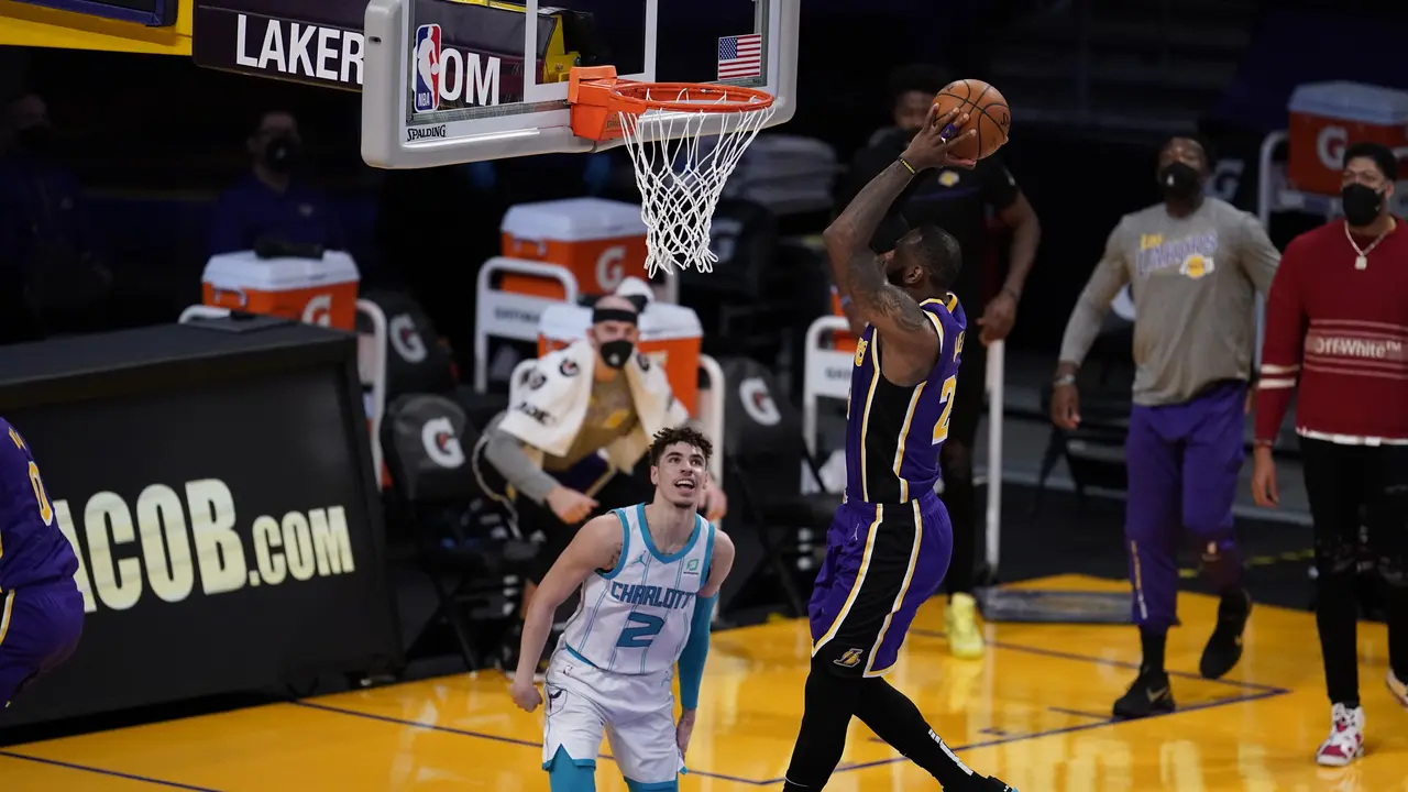 Pebasket Los Angeles Lakers, LeBron James, melakukan dunk di depan pemain Charlotte Hornets, LaMelo Ball.