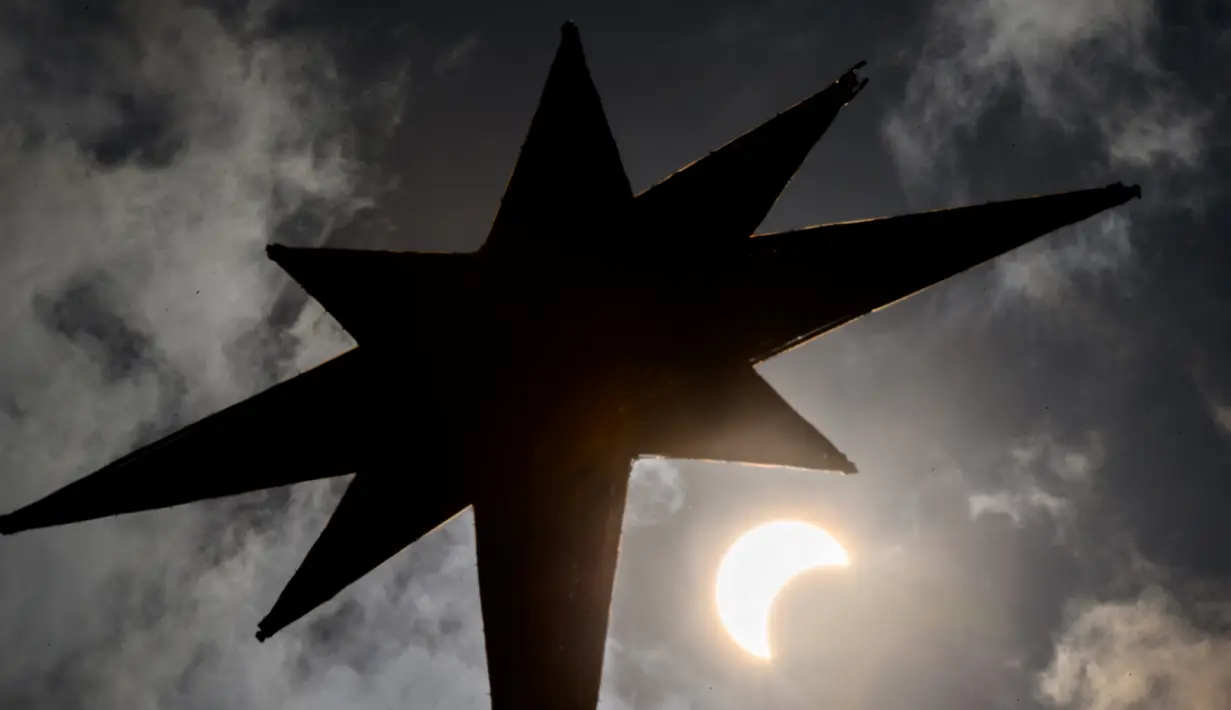 Bulan mulai menutupi matahari saat gerhana matahari cincin di Bangkok, Thailand, Kamis (26/12/2019). Gerhana matahari cincin ini dapat diamati dari sejumlah wilayah mulai dari Afrika timur, seluruh Asia, Samudera India, dan Australia utara. (Lillian SUWANRUMPHA/AFP)